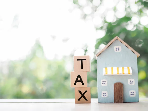Miniature house and Wooden blocks with the word TAX. The concept of payment tax for house, Property investment, House mortgage, Real estate