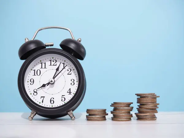 Black alarm clock and stack of coins. The concept of saving money, manage time to business achievement goal, Financial, Investment and Business growing