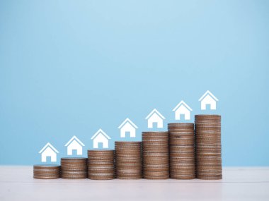 Minyatür ev ikonları ve bozuk para yığını. Ev için para biriktirme kavramı, emlak yatırımları, ev kredisi, gayrimenkul..