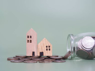 Minyatür ev ve bozuk para yığını. Ev için para biriktirme kavramı, emlak yatırımları, ev kredisi, gayrimenkul..
