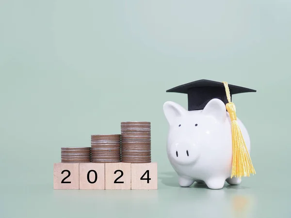 Study goals, Piggy bank with graduation hat and stack of coins. The concept of saving money for education, student loan, scholarship, tuition fees in New Year 2024