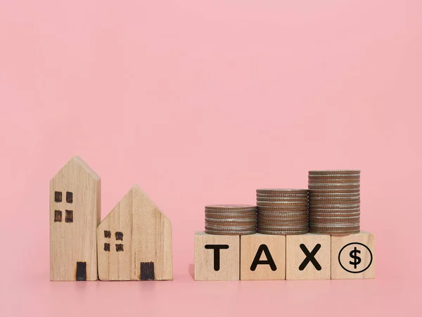 Miniature house, Wooden blocks with the word TAX and stack of coins. The concept of payment tax for house, Property investment, House mortgage, Real estate.