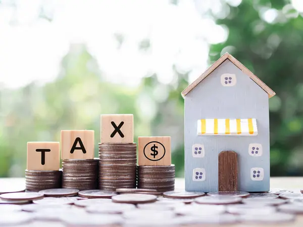 Miniature house, Wooden blocks with the word TAX and stack of coins. The concept of payment tax for house, Property investment, House mortgage, Real estate.