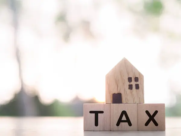 Miniature house and Wooden blocks with the word TAX. The concept of payment tax for house, Property investment, House mortgage, Real estate