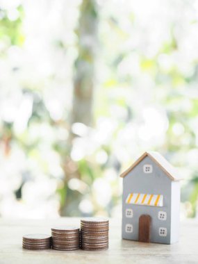 Minyatür ev ve bozuk para yığını. Ev için para biriktirme kavramı, emlak yatırımları, ev kredisi, gayrimenkul.
