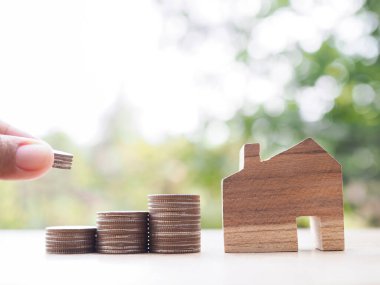 Bozuk para ve minyatür evin içine madeni paralar koymak için elinizi kapatın. Ev için para biriktirme kavramı, emlak yatırımları, ev kredisi, gayrimenkul.