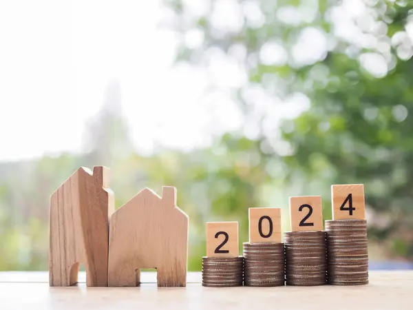 Miniature house and Wooden block with number 2024 on stack of coins. The concept of payment tax for house, Property investment, House mortgage, Real estate in year 2024.