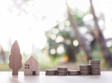 Minyatür ev ve bozuk para yığını. Ev için para biriktirme kavramı, emlak yatırımları, ev kredisi, gayrimenkul.