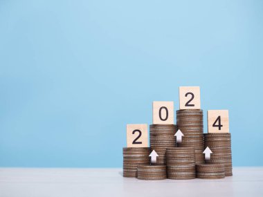 2024 numaralı tahta bloklar bozuk para yığınının üzerinde. 2024 yılında para, finans, yatırım ve işletme tasarruf kavramı büyüyor.