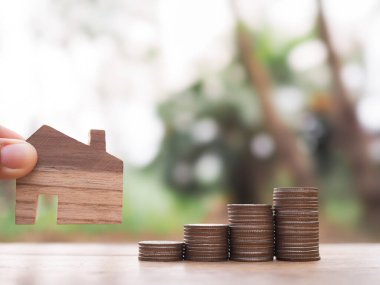 Minyatür ev ve bozuk para yığını. Ev için para biriktirme kavramı, emlak yatırımları, ev kredisi, gayrimenkul.