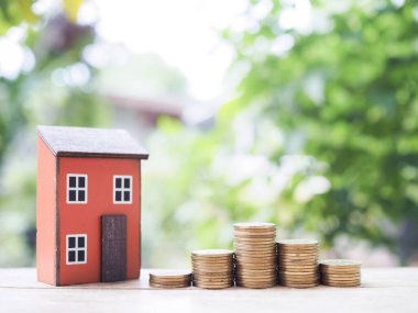 Minyatür ev ve bozuk para yığını. Ev için para biriktirme kavramı, emlak yatırımları, ev kredisi, gayrimenkul.