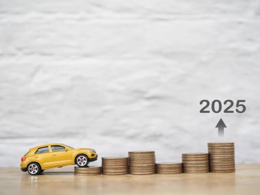 Oyuncak araba bozuk para yığınının üzerinde. 2025 yılında para biriktirme ve başarılı ulaşım işi kavramı
