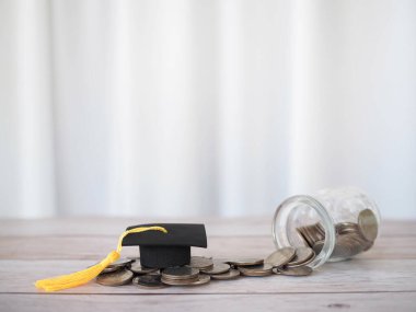 Mezuniyet şapkası ve bozuk para yığını. Eğitim, öğrenci kredisi, burs, eğitim ücretleri için para biriktirme kavramı