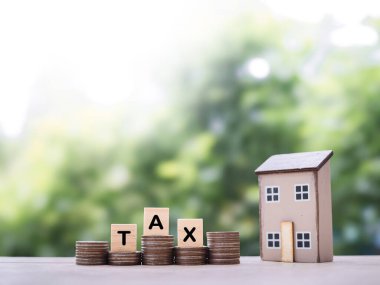 Minyatür ev ve ahşap bloklar. Üzerinde de vergi yazıyor. Konut kredisi, emlak yatırımı, ev kredisi, emlak vergisi kavramı