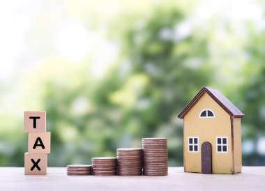 Minyatür ev, tahtadan bloklar, vergi ve bozuk para yığını. Konut kredisi, emlak yatırımı, ev kredisi, emlak vergisi kavramı