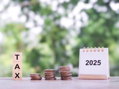 2025 masa takvimi, tahtadan bloklar, vergi ve bozuk para yığını. 2025 yılında vergi ödemek için para biriktirme ve zamanı yönetme konsepti