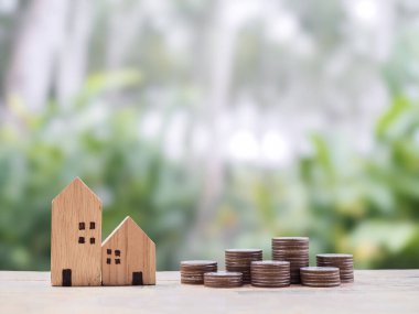 Minyatür ev ve bozuk para yığını. Ev için para biriktirme kavramı, emlak yatırımları, ev kredisi, gayrimenkul..