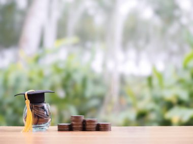 Glass bottle with graduation hat and stack of coins. The concept of saving money for education, student loan, scholarship, tuition fees in the future clipart