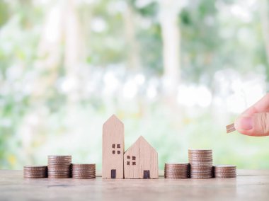 Bozuk paralar ve minyatür ev için el sıkışın. Ev için para biriktirme kavramı, emlak yatırımları, ev kredisi, gayrimenkul.