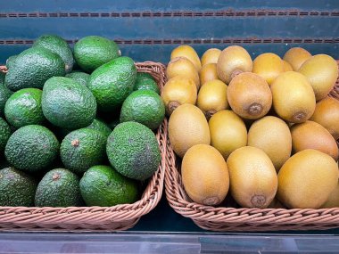 Süpermarkette satmak için taze organik avokadolar ve sepetteki altın kivi..