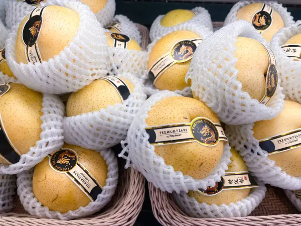 RAYYONG, THAILAND - 1 HAZİRAN 2025: Kar süpermarkette satmak için ahşap sepete armut koyar