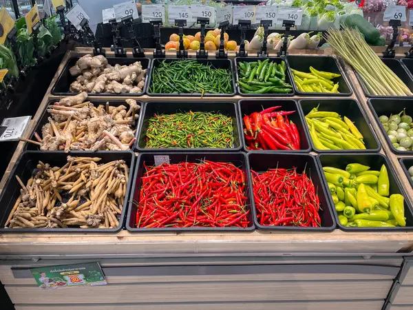 RAYONG, THAILAND - 1 Haziran 2025: Süpermarkette satılmak üzere taze organik sebzeler sepeti. Kırmızı biber, zencefil, galangal, limon otu, parmak kökü