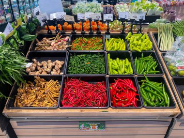 RAYONG, THAILAND - 21 Haziran 2025: Süpermarkette satılmak üzere taze organik sebzeler sepeti. Kırmızı biber, zencefil, galangal, limon otu, parmak kökü