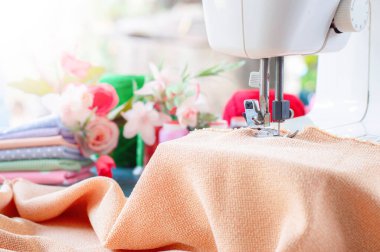 Kahverengi kumaşla çalışan dikiş makinesi, masaya aksesuar dikmek, yeni kıyafetler dikmek..