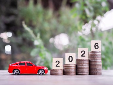 Oyuncak arabalar ve tahta bloklar. 2026 numaralı madeni para yığını. 2026 yılında para biriktirme ve başarılı ulaşım işi kavramı.