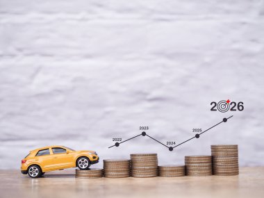 Oyuncak araba ve sanal olarak artan grafiği olan bozuk paralar. Başarılı ulaşım için para biriktirme kavramı, 2026 yılında araba kredisi