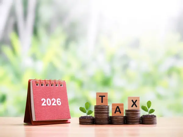 2026 masa takvimi, tahtadan bloklar, vergi ve bozuk para yığınları üzerinde büyüyen bitkiler. 2026 yılında vergi ödemek için para biriktirme ve zamanı yönetme konsepti