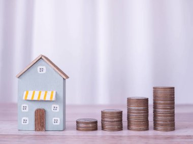 Minyatür ev ve bozuk para yığını. Ev için para biriktirme kavramı, emlak yatırımları, ev kredisi, gayrimenkul..