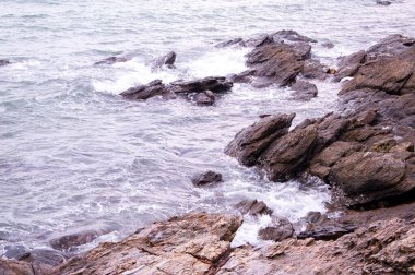 Deniz dalgaları su sıçramalarıyla kayalara çarpıyor.