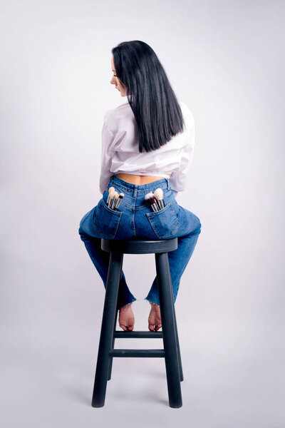 Beautiful sexy female buttocks in jeans with makeup brushes in pockets. Makeup and cosmetics concept