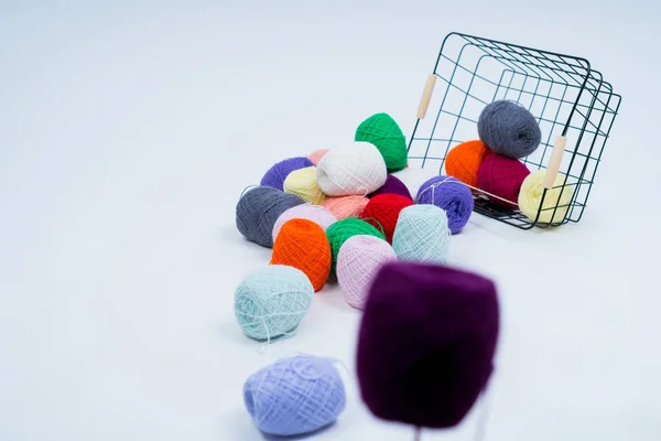 Multi-colored balls of thread. Overturned basket with multi-colored balls of thread isolated on a white background.