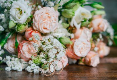 Düğün buketinin arka planında iki alyans.