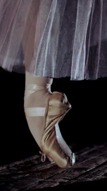 eski tiyatro salonu sahnede spot, ışınları kapatın. Balerin yükseltir ayak pointe ayakkabı, beyaz bale etekle zarif gerçekleştirir belirli bir bale egzersiz, pointe, tendu.