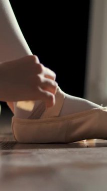 Yakın plan. Kız sivri uçlu ayakkabılar giyer, sivri uçlu ayakkabılar bağlar, bale çalışmak için, koridorda yerde oturmak için. Bale dersleri, klasik bale okulu..