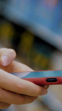 Süpermarkette cep telefonu. Markette akıllı telefon kullanmak. Yakın plan. Arka planda süpermarket raflarında telefonu olan eller. Birisi süpermarkette günlük yiyecek alışverişi yaparken akıllı telefon kullanıyor..