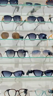 Güneş gözlüğü. Moda gözlüklerinin farklı modelleri olan bir vitrin. Gözlük. Alışveriş. Perakende mağazasından güneş gözlüğü almak. Optik dükkanı...