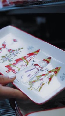 Noel sofra takımı. Noel tabağı. Yakın plan. Bir süpermarkette ya da alışveriş merkezinde, kadın güzel bir Noel tabağına bakar. Şenlikli Noel masası.