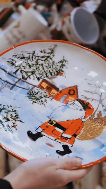 Noel tabağı, tabak, çatal bıçak. Burada. Yakın plan. Kadınlar Noel aksesuarlarına, mağazalardaki dekorasyonlara, süpermarketlere ya da Noel fuarlarına bakarlar. Hediye almaya gidiyorum. vitrin. Noel ruhu. İyi tatiller. Yeni Yıl.