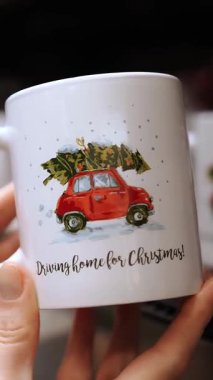 Noel kupası. Burada. Noel hediyesi. Yakın plan. Bayram kadehi bayanların elinde. Noel aksesuarları, dekor, bir mağazada ya da süpermarkette süslemeler. Noel ruhu. Mutlu tatiller..