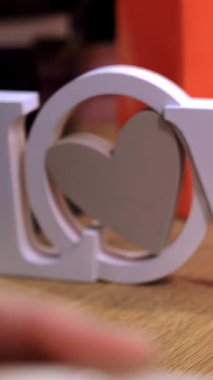 Sevgililer Günü. Yakın plan. Arkaplanda ahşap harfler var. Küçük kahve fincanlarında kırmızı kalpler ve ellerinde aşk yazıları var. Sevgililer gününde hediye, duyguların ve sevginin ifadesi olarak. Sevgililer Günü için alışveriş konsepti.