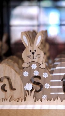 Paskalya indirimi. Paskalya süslemeleri ve dükkandaki ev için hediyeler. Geleneksel Paskalya tavşanları ve yumurtalarıyla tahta, kontraplaktan oyulmuş dekoratif Paskalya Paskalyası bir mağazada sergileniyor. Katolik Paskalyası