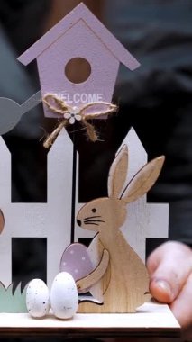 Paskalya panayırı. Yakın plan. Paskalya süslerini tutan kadın elleri. Tavşanlar, kuşlar ve yumurtalarla güzel bir Paskalya kompozisyonu. Katolik Paskalyası için geleneksel Avrupa dekorasyonu