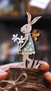 Paskalya panayırı. Yakın plan. Paskalya süslerini tutan kadın elleri. Paskalya tavşanının komik biblosu. Katolik Paskalyası için geleneksel Avrupa dekorasyonu