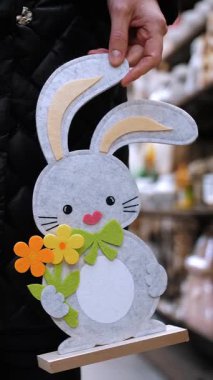 Paskalya panayırı. Yakın plan. Paskalya süslerini tutan kadın elleri. Paskalya tavşanlarının komik figürleri. Katolik Paskalyası için geleneksel Avrupa dekorasyonu