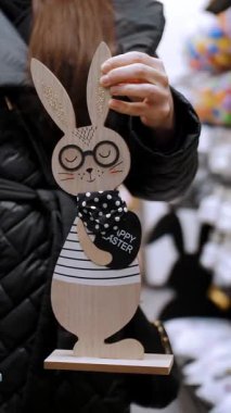 Paskalya panayırı. Yakın plan. Paskalya süslerini tutan kadın elleri. Paskalya tavşanlarının komik figürleri. Katolik Paskalyası için geleneksel Avrupa dekorasyonu