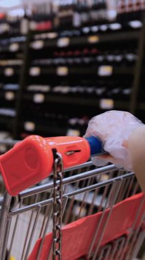 Sağlık Güvenliği Tedbirli Şarap Alışverişi. Market alışverişi sırasında alışveriş arabasıyla süpermarket koridorunda gezen bir müşteri. Yüksek kalite 4k görüntü